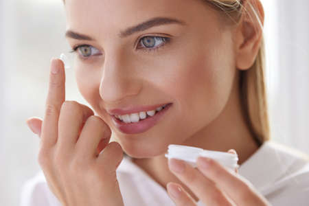 Eye care. Smiling Woman With Contact Eye Lens on Finger Closeupの写真素材