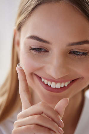 Eye care. Smiling Woman With Contact Eye Lens on Finger Closeupの写真素材