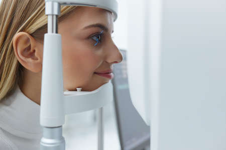 Eyesight Exam. Woman Checking Eye Vision On Optometry Equipmentの写真素材