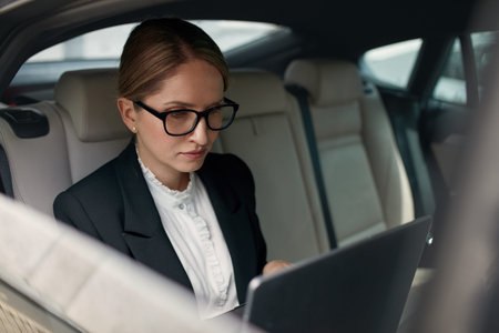 Serious Concentrated Business Woman 60-65 Years Using Laptop in Car