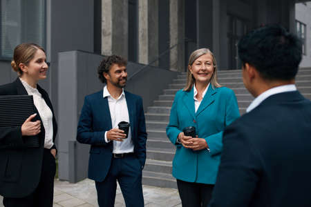 Smiling Coworkers With Coffee Near Building. Business People Having Conversationの写真素材