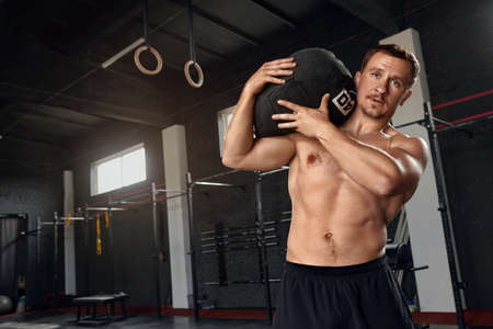 Portrait Of Handsome Muscular Man Holding Heavy Weight In Gymの写真素材