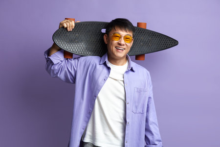 Smiling Man Holding Skateboard. Asian Guy Holding Longboard on Shoulderの写真素材