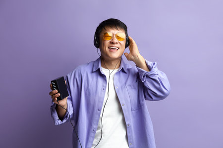 Asian Man Listening Music. Positive Man Listening Radio in Earphones and Dancingの写真素材