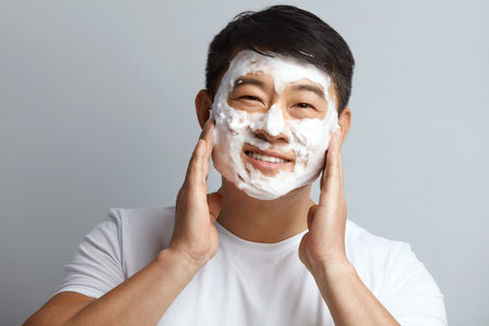 Man Face Skin Care. Asian Model Cleaning Face With White Foam During Spaの写真素材