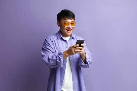 Happy Man Using Smartphone. Asian Guy Smiling while Using Cellphoneの写真素材