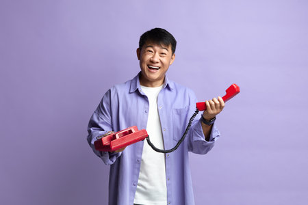 Man Talking Landline Telephone. Asian Man Speaking on Retro Phone and Smilingの写真素材