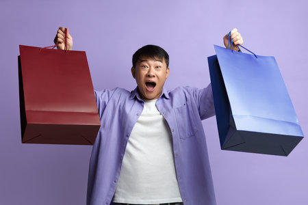 Happy Man Enjoying Shopping. Satisfied Guy Holding and Showing Shopping Bagsの写真素材