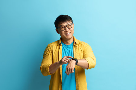 Asian Man Pointing Watch. Cheerful Punctual Guy Pointing at Wrist Watchの写真素材