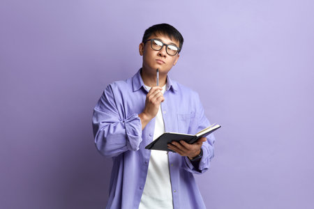 Asian Man Writing Notebook. Portrait of Guy Making Notes in Paper Notebookの写真素材