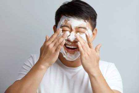 Man Face Skin Care. Asian Happy Guy Cleansing Face with Foam Soapの写真素材