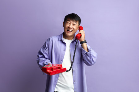 Man Talking Landline Telephone. Asian Man Speaking on Retro Phone and Smilingの写真素材
