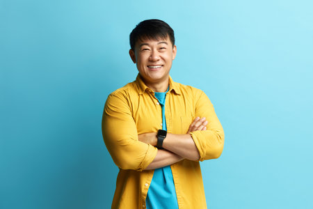 Smiling Man Posing Studio. Portrait of Asian Businessman Standing Crossed Handsの写真素材