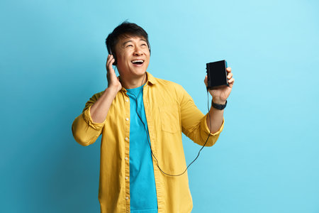 Asian Man Listening Music. Positive Man Listening Radio in Earphones and Dancingの写真素材