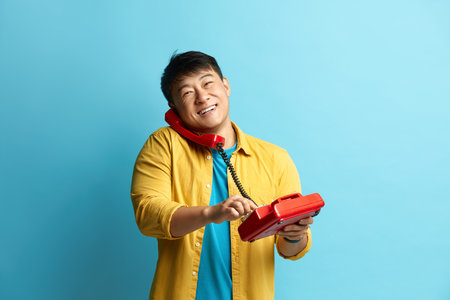 Man Talking Landline Telephone. Asian Man Speaking on Retro Phone and Smilingの写真素材