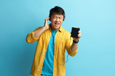 Asian Man Listening Music. Positive Man Listening Radio in Earphones and Dancingの写真素材