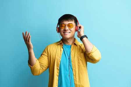 Asian Man Listening Music. Positive Man Listening Song Wearing Headphonesの写真素材