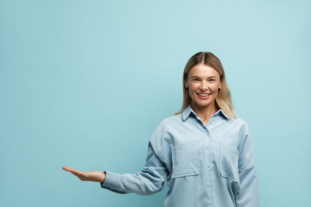 Laughing Woman Pointing Palm Away. Girl Gesturing with Smile at Empty Spaceの写真素材