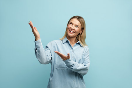 Positive Woman Pointing Palms Away. Girl Gesturing with Smile on Empty Spaceの写真素材