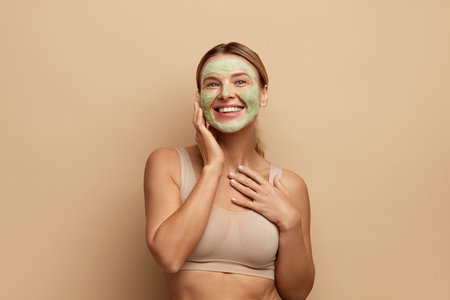 Positive Woman with Face Mask. Closeup Female Applying Green Clay Mask On Faceの写真素材