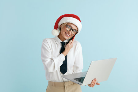 Happy Christmas Businesswoman Answering Call. Woman in Santa Hat Holding Laptopの写真素材