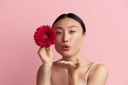 Skin Care Woman Posing with Red Flower. Asian Model Sending Kiss Holding Flowerの写真素材