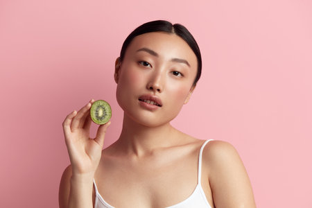 Healthy Nutrition. Portrait Of Asian Woman Posing with Green Kiwiの写真素材