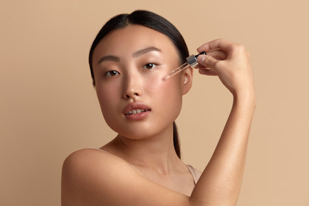 Woman Applying Serum on Face. Woman Applying Essential Oil On Facial Skinの写真素材