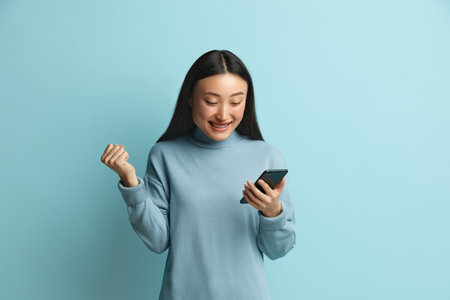 Rejoicing Woman Holding Smartphone Isolated. Asian Girl Messaging Cellphoneの写真素材