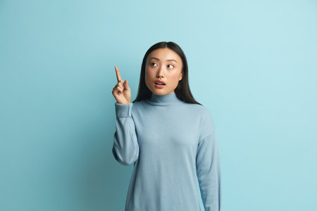 Happy Woman Pointing Aside. Amused Asian Girl Points Fingers Awayの写真素材