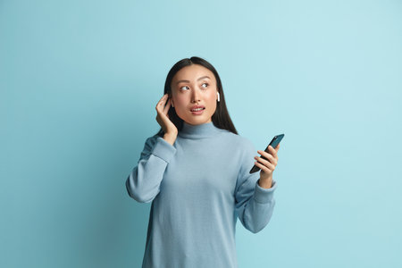 Asian Woman Listening Music. Pleased Woman Wireless Earphones Listening Melodyの写真素材