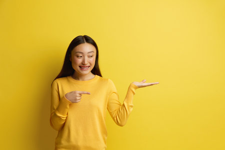 Smiling Woman Pointing Aside. Amused Young Girl Points Finger Awayの写真素材