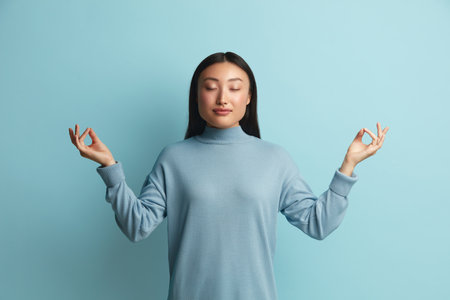 Peaceful Woman Meditating at Studio. Asian Girl Doing Meditation Gestureの写真素材
