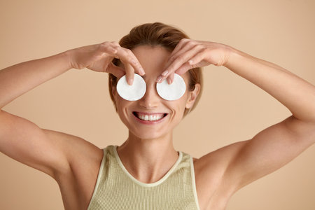 Laughing Woman Cleaning Face With White Pad. Girl Having Fun With Cotton Padの写真素材
