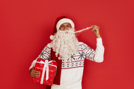 Santa Holding New Year Present. Multiracial Guy With Beard Carrying Gift Boxの写真素材