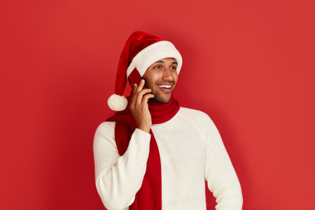 Happy Man Using Smartphone. Multiracial Guy Santa Hat Smiling Calling Cellphoneの写真素材