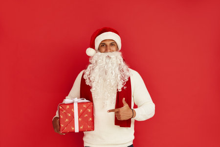 Man Pointing New Year Present. Guy in Santa Hat Paying Attention at Gift Boxの写真素材