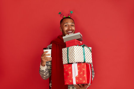 Happy Man Holding Present. Guy Holding in Coffee to Go and Present Boxesの写真素材