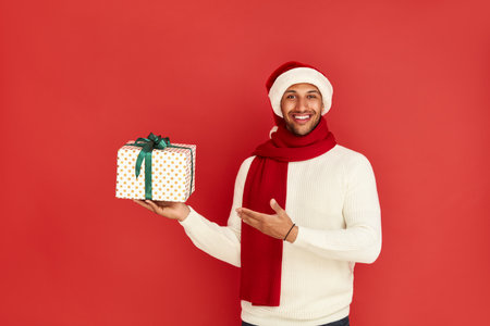 Man Pointing New Year Present. Guy in Santa Hat Paying Attention at Gift Boxの写真素材
