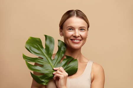 Skin Care Woman Posing with Green Leaf. Caucasian Model Holding Tropical Plantの写真素材