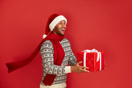Happy Man Holding Present. Multiracial Guy in Santa Hat Holding Present Boxの写真素材