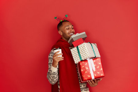 Happy Man Holding Present. Guy Holding in Coffee to Go and Present Boxesの写真素材