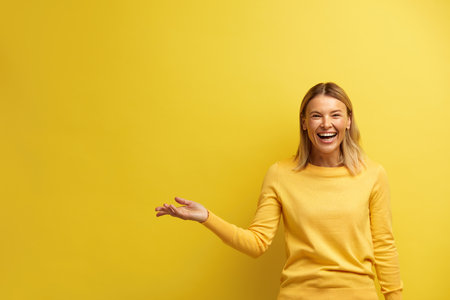 Laughing Woman Pointing Palm Away. Blonde Girl Gesturing at Empty Spaceの写真素材