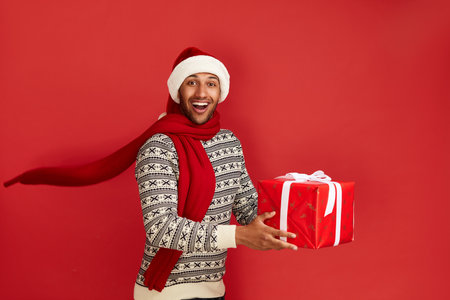 Happy Man Holding Present. Multiracial Guy in Santa Hat Holding Present Boxの写真素材