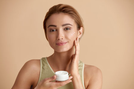 Beauty Woman Applying Face Cream. Closeup Of Female Model Holding Cream Bottleの写真素材