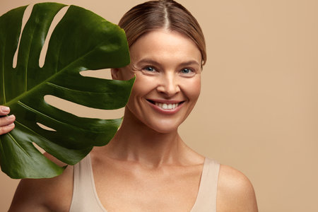 Skin Care Woman Posing with Green Leaf. Caucasian Model Holding Tropical Plantの写真素材