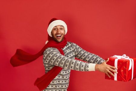 Happy Man Holding Present. Multiracial Guy in Santa Hat Holding Present Boxの写真素材