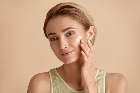 Skin Care Woman Applying Cream on Cheek. Closeup Of Smiling Girl Putting Creamの写真素材