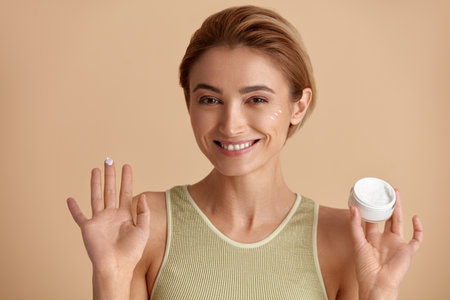 Caucasian Woman Applying Cream. Closeup Of Model With Fresh Skin Holding Bottleの写真素材