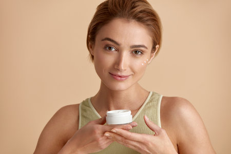 Beauty Woman Applying Face Cream. Closeup Of Female Model Holding Cream Bottleの写真素材